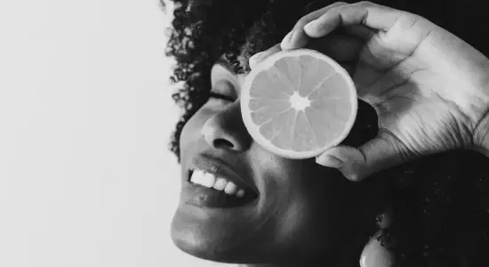 Vitamincheck frau mit orangenscheibe vor dem gesicht